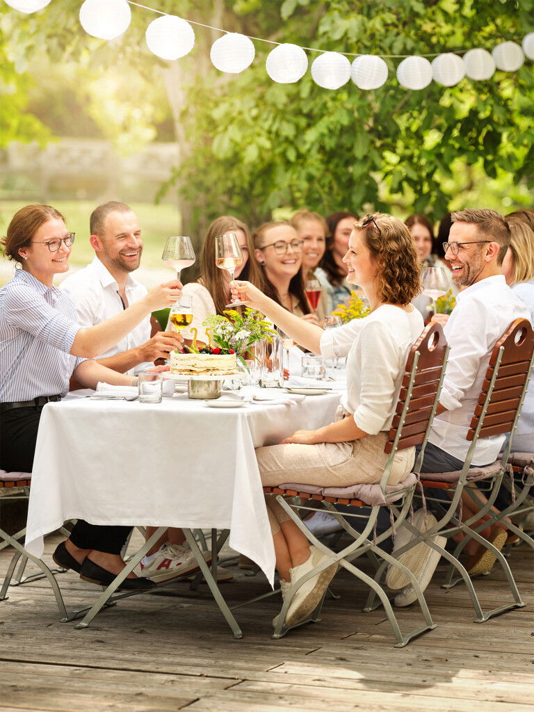 Personen sitzen an einem Tisch und stoßen an