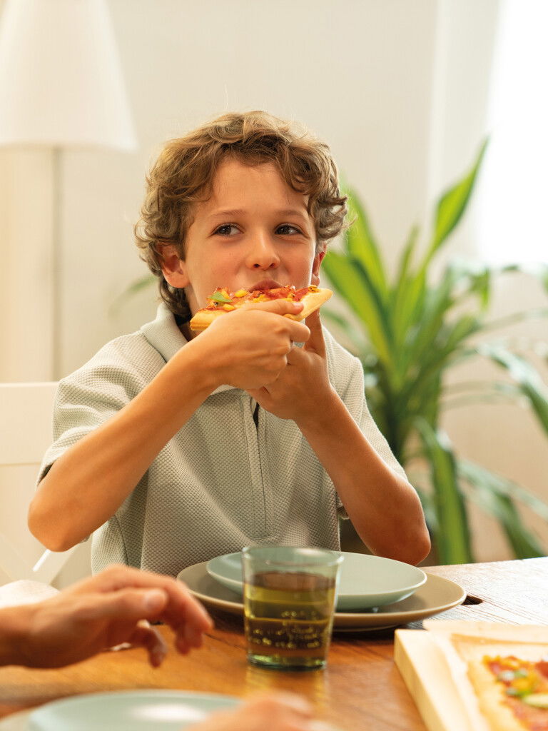 Junge beißt in ein Stück Pizza