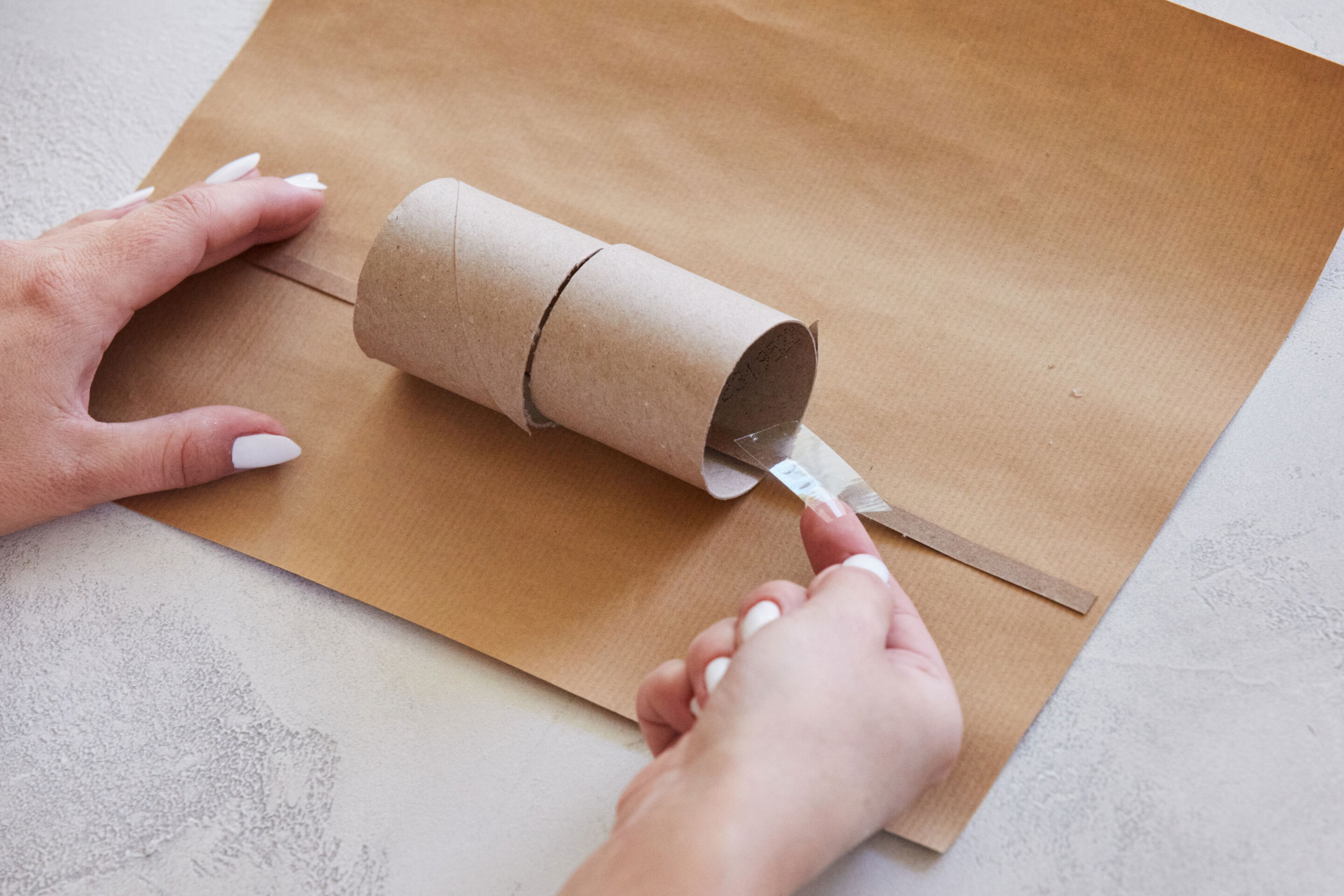 Schritt 4: Klebe die zweite Hälfte der Klopapierrolle auf dieselbe Art und Weise am Geschenkpapier fest.